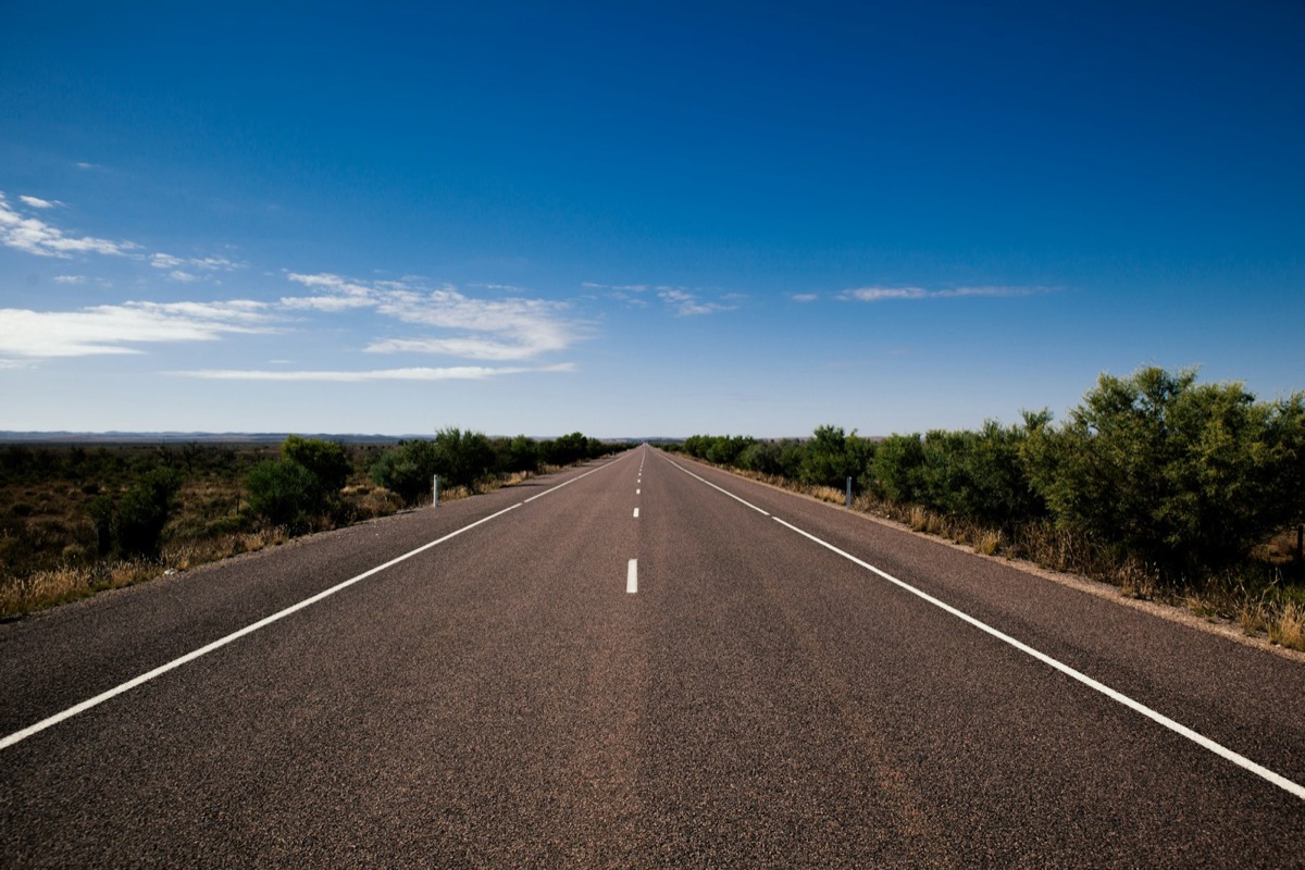 Long empty asphalt test track under a clear blue sky
